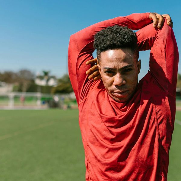 Man feeling energized and stretching outdoors with the sun in the background.