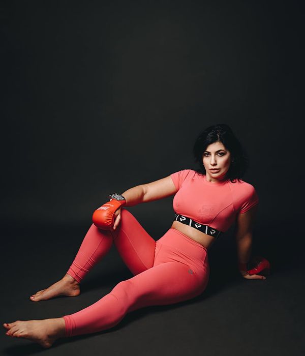 Woman in activewear performing a dynamic cardio stretch in a modern studio.